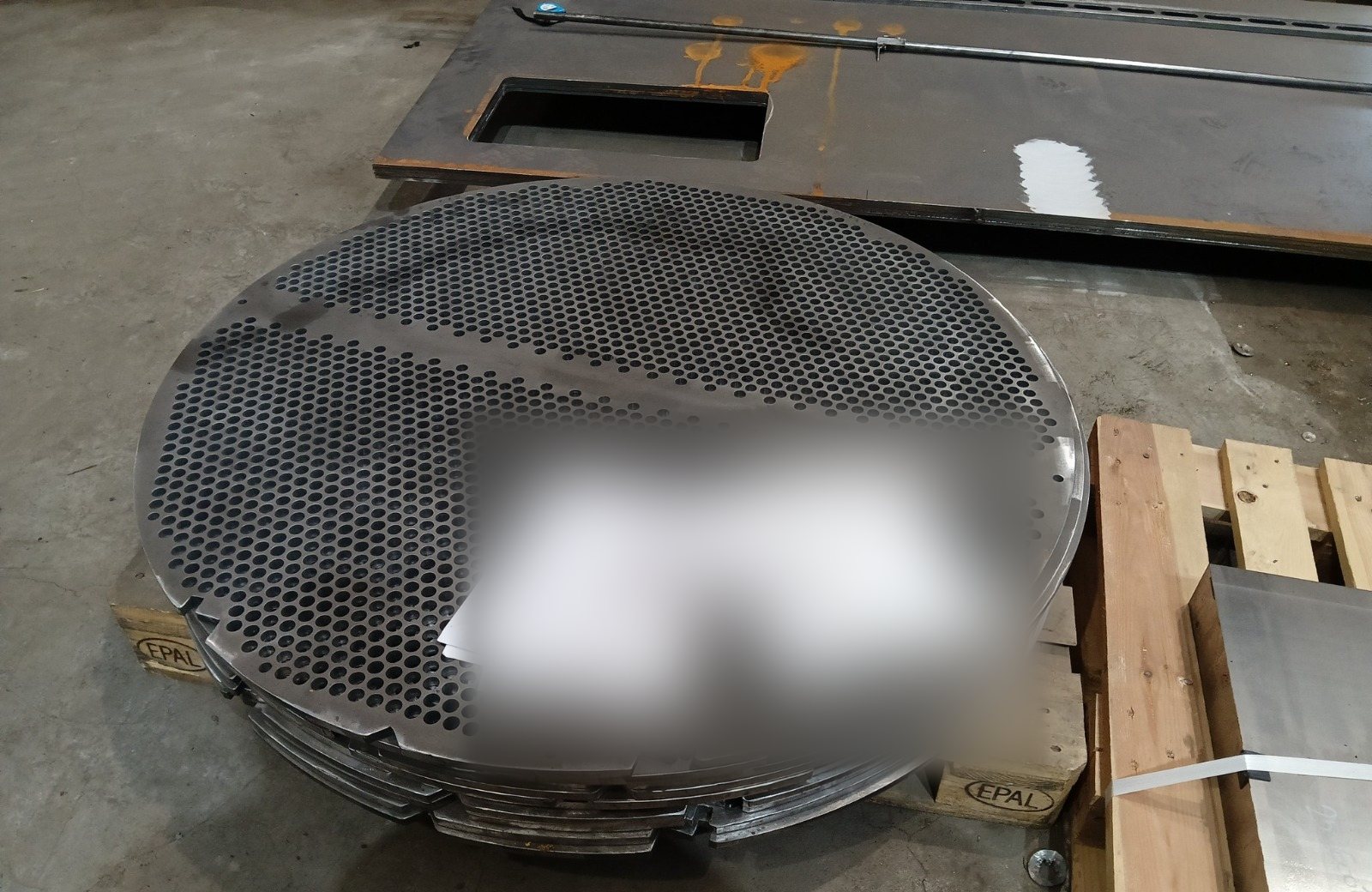 Stack of drilled baffle plates for a heat exchanger tube bundle, showing the pass-partition lane