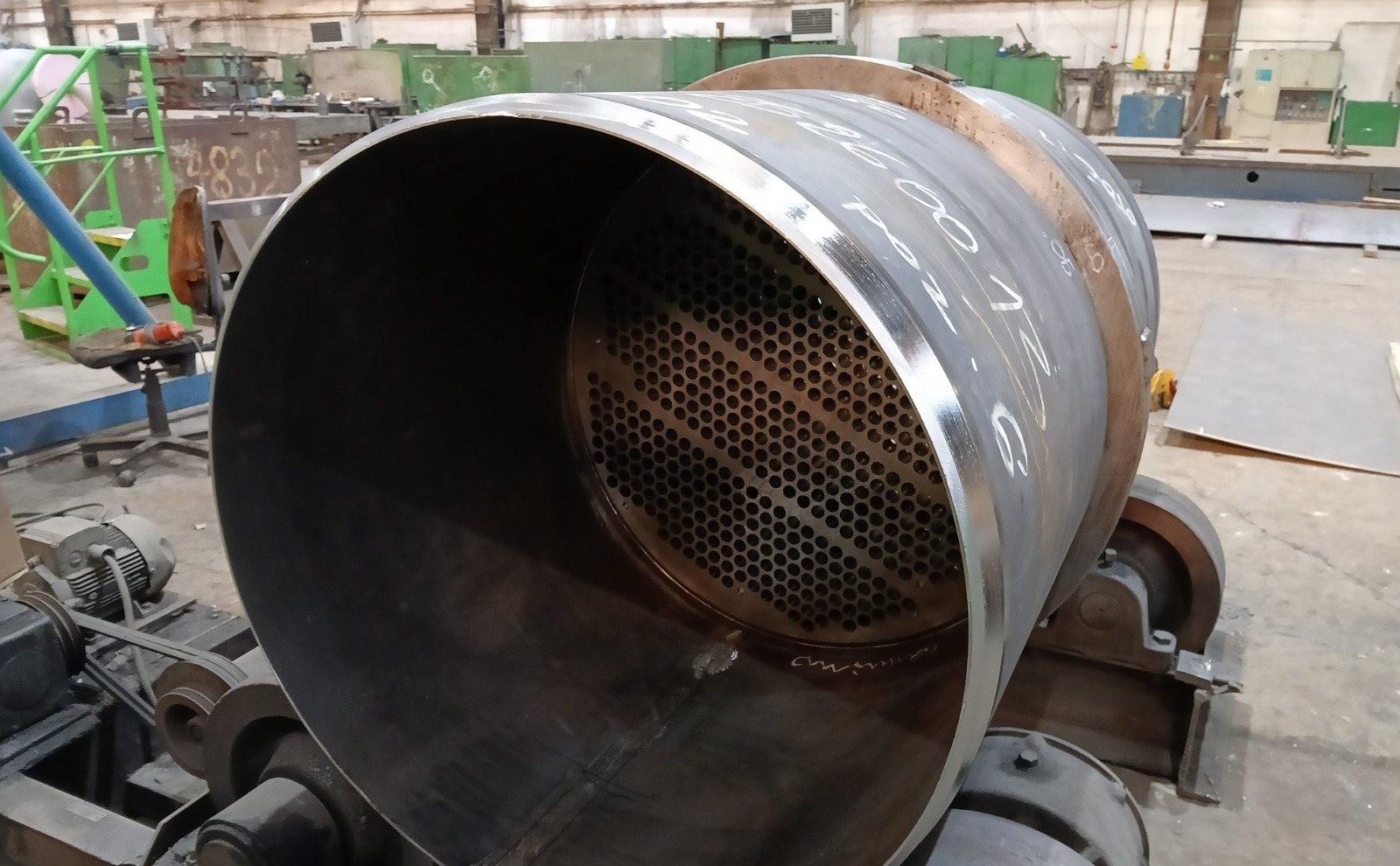 Heat exchanger shell section on turning rolls with a drilled tube plate visible inside